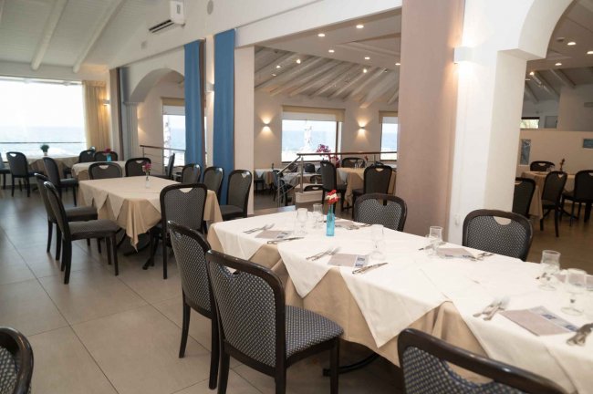 Sala da pranzo elegante con tavoli apparecchiati e ampie finestre.