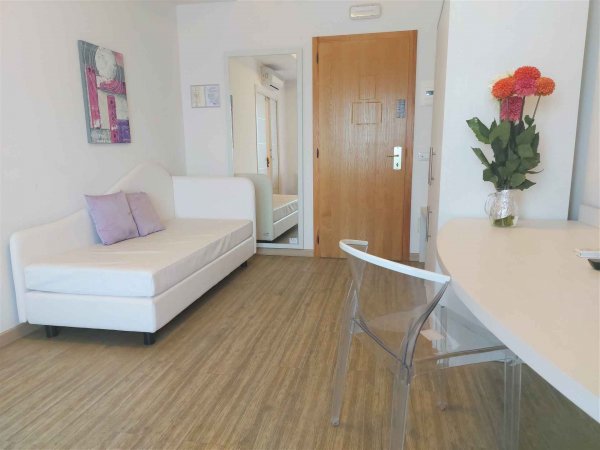 Stanza con divano bianco, tavolo e fiori colorati.