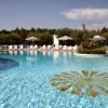 Piscina con sdraio e ombrelloni, circondata da alberi.