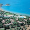 Vista aerea di un villaggio turistico con spiaggia e mare azzurro.