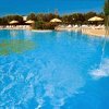 Piscina con cascata d'acqua, ombrelloni e lettini intorno.
