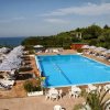 Piscina all'aperto con lettini e ombrelloni a righe.