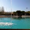 Cascata d'acqua in una piscina con lettini sullo sfondo.