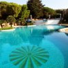 Piscina con disegni sul fondo e circondata da alberi.