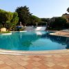 Piscina circolare con sedie a sdraio, vegetazione sullo sfondo.