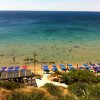 Spiaggia con ombrelloni blu e mare trasparente, vista dall'alto.