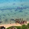 Gruppo di persone sulla riva del mare cristallino.