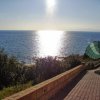 Sentiero lastricato conduce al mare, illuminato dal sole.
