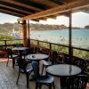 Terrazza con tavoli e sedie, vista mare e bagnanti in acqua.