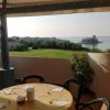 Tavolo apparecchiato su terrazza con vista su prato e mare.