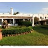 Un edificio bianco con tetto in tegole, circondato da un giardino verde curato.
