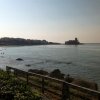 Vista su un mare calmo con una spiaggia a sinistra e un castello in lontananza.
