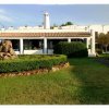 Una casa bianca con tetto in tegole e un giardino ben curato con siepi e rocce.