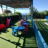 Un'area giochi per bambini con tavolini e sedie colorate sotto una tettoia azzurra.
