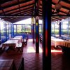 Un'area pranzo coperta con tavoli e panche in legno e ampie finestre.