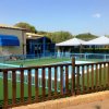 Area esterna con piscina recintata, tende blu e verdeggianti dintorni.