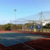 Un campo sportivo con basket e reti protettive, attrezzato per diversi sport.
