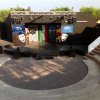 Un palco all'aperto con sedili semicircolari e maschere teatrali dipinte.