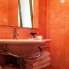 Bagno con piastrelle arancioni, lavandino bianco e asciugamani sotto.