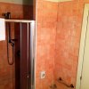 Bagno con piastrelle arancioni, doccia moderna e asciugamano bianco.