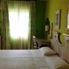 Camera da letto con pareti verdi, tenda chiara e mobili in legno chiaro.