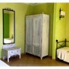 Camera da letto con armadio bianco, specchio a muro e letto singolo, su pareti verde chiaro.