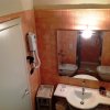 Bagno con piastrelle arancioni, lavabo con specchio e asciugacapelli a muro.