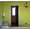 Interno di una camera da letto verde con vista su un bagno con porta socchiusa.