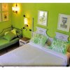 Camera da letto verde con letto matrimoniale, divano letto e quadri alle pareti.