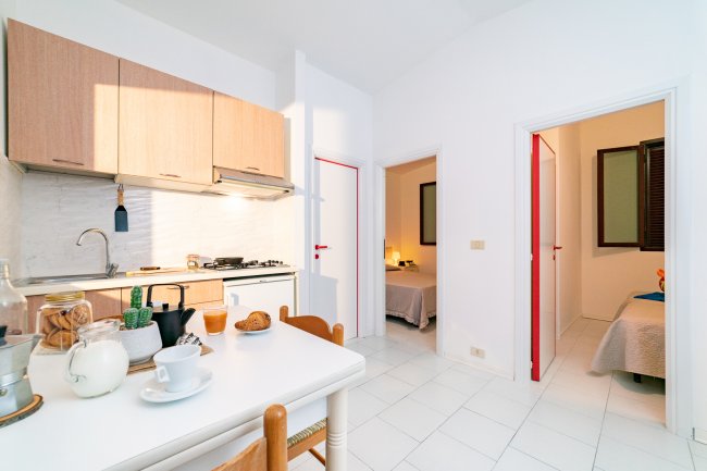 Cucina luminosa con tavolo apparecchiato e due ingressi.