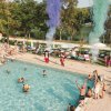 Piscina all'aperto con persone e fumo colorato.