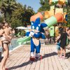 Mascotte blu vicino a piscina e scivoli.