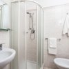Bagno moderno con doccia ad angolo, lavabo e bidet. Asciugamani appesi.