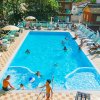 Una piscina con persone che nuotano e prendono il sole su lettini.