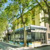 Strada alberata con un edificio moderno a più piani sulla destra.