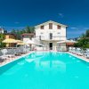 Vista sulla piscina vuota con lettini e ombrelloni, edificio sullo sfondo.