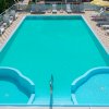 Vista dall'alto di una piscina rettangolare con scalette e lettini sui lati.