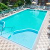 Piscina all'aperto con sdraio e ombrelloni gialli a strisce.