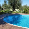 Piscina rotonda all'aperto circondata da vegetazione e alberi.