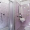 Bagno con piastrelle rosa e doccia.