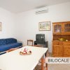 Soggiorno con tavolo, credenza in legno e divano blu.