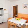 Cucina con tavolo, divano arancione e mobili bianchi.