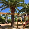 Parco giochi con altalena e palme.