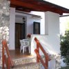 Veranda con pareti in pietra, tavolo e sedie bianche.