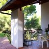 Veranda con tavolo e sedie bianche, vista sul giardino alberato.