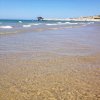 Spiaggia con acqua limpida e una nave in lontananza.