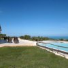 Piscina e prato con mare in lontananza.