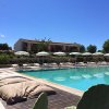 Piscina con lettini e cuscini, edificio sullo sfondo.