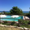 Piscina con ombrelloni e vista mare.