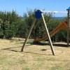Parco giochi con altalena e scivolo vicino al mare.
